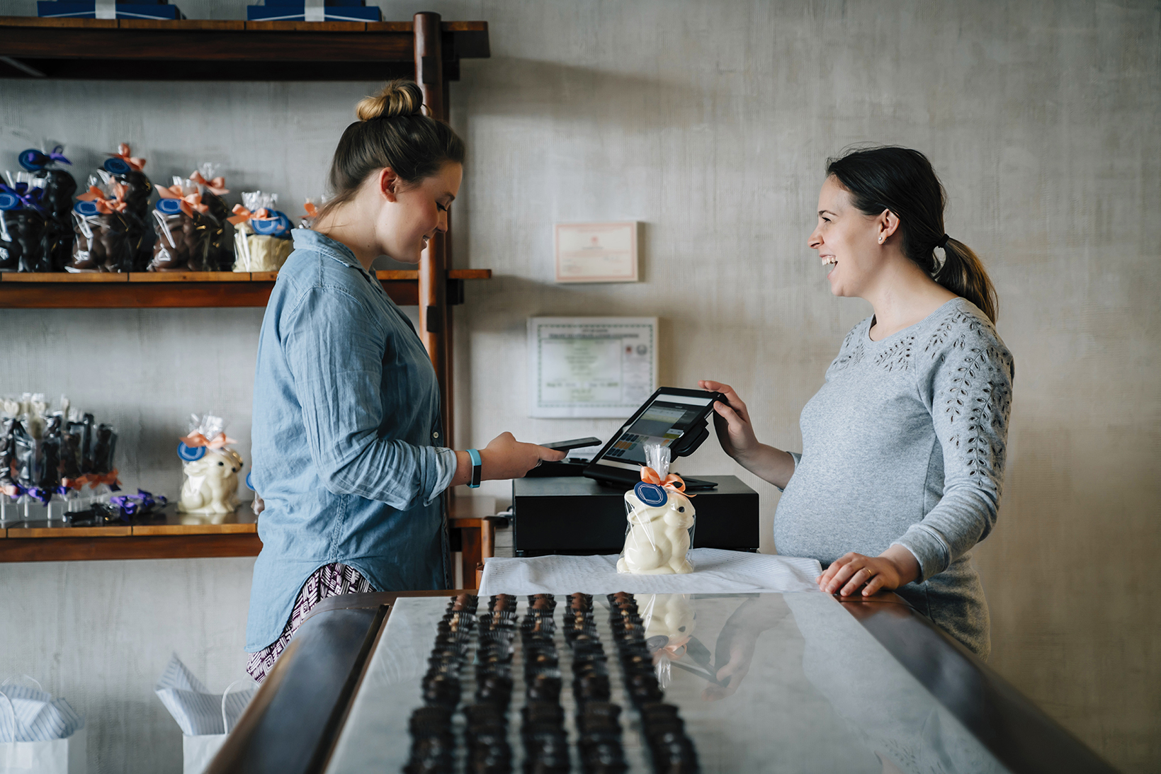 An image of two women, one is being served by the other across a counter in a store.