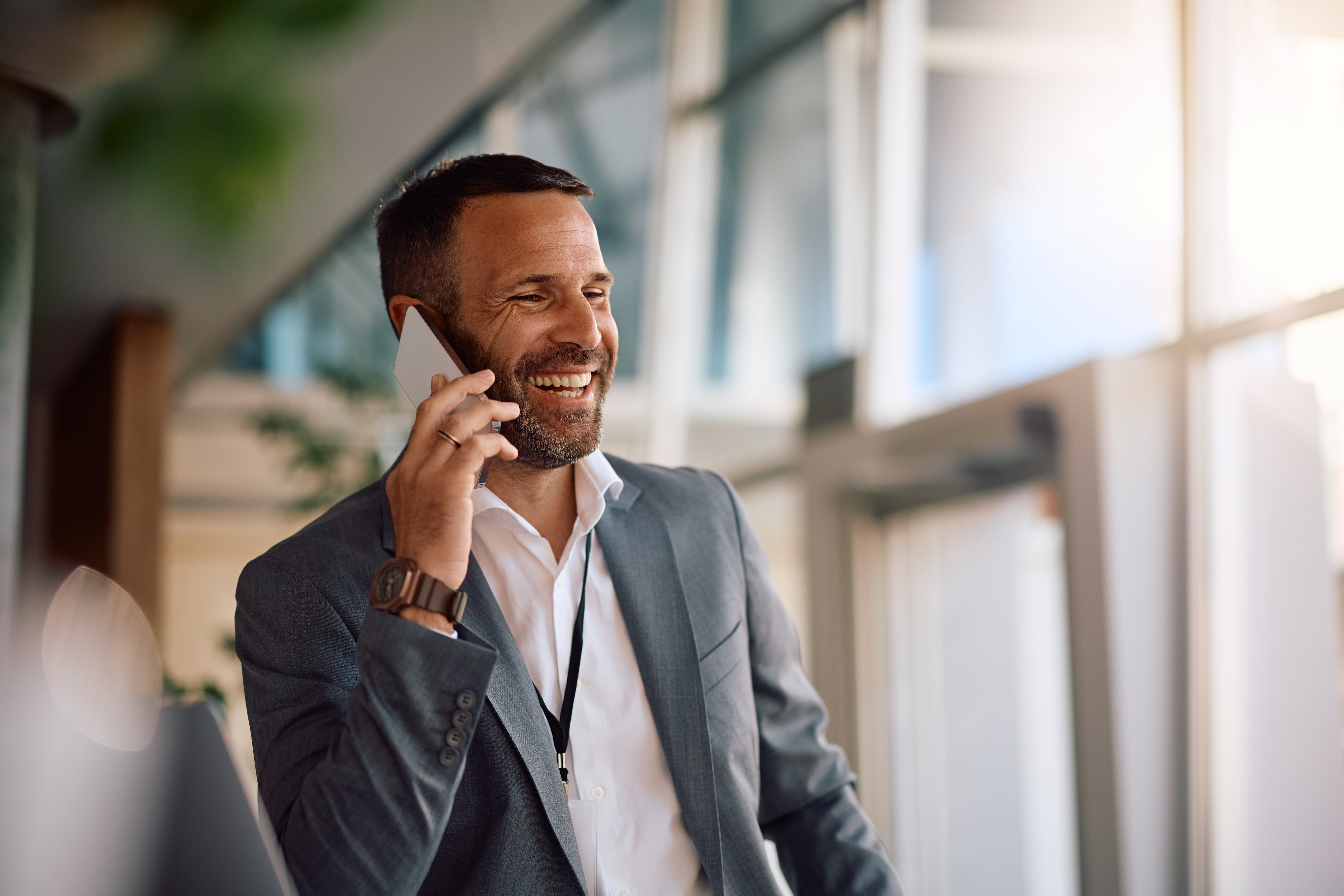 An image of a man in a suit smiling while on the phone
