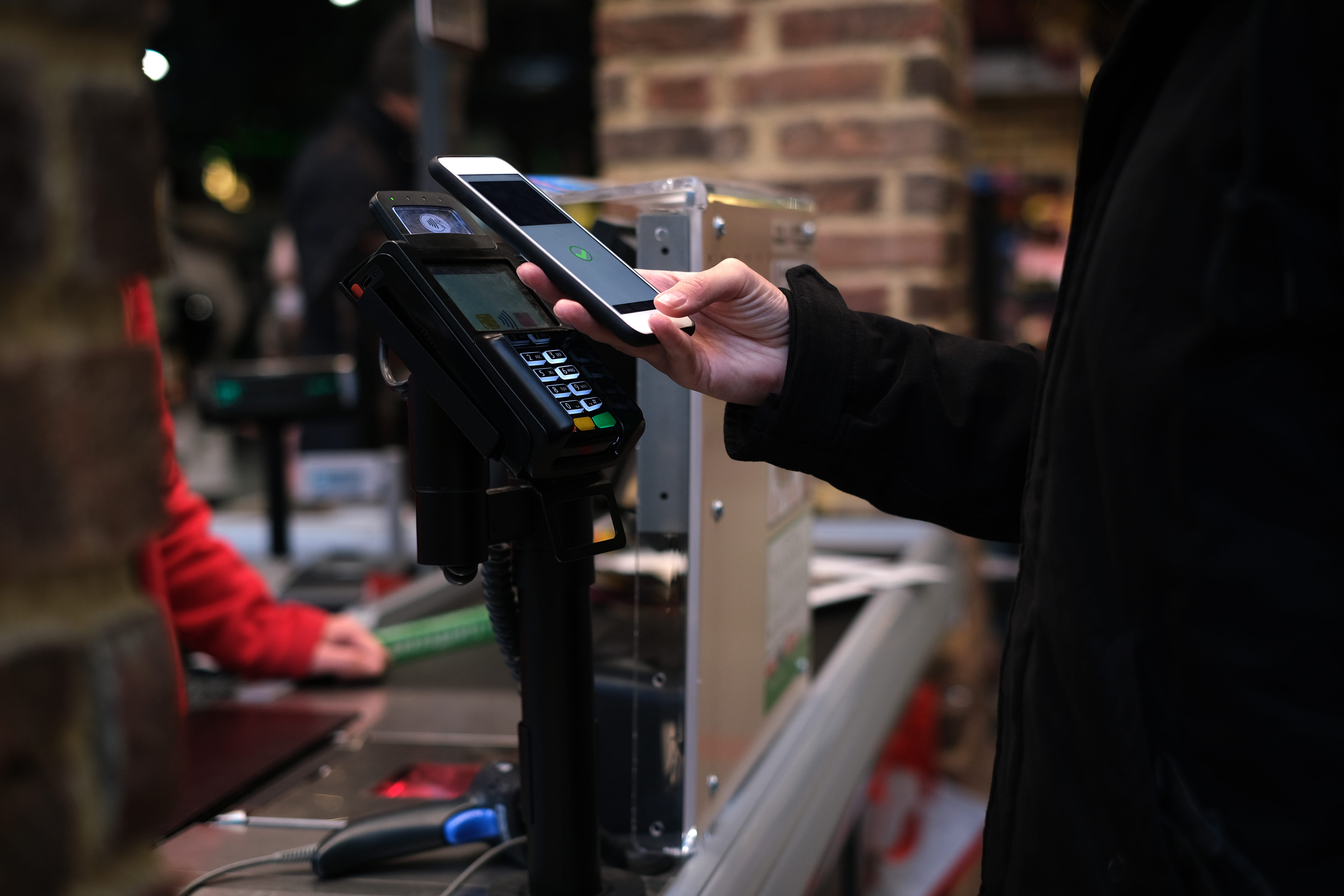 An image of a hand holding a phone against an eftpos machine.