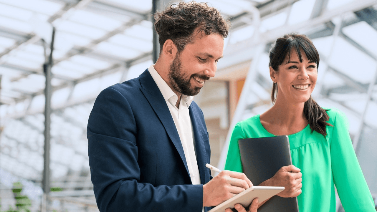 Man and woman conducting a meeting while taking notes and smiling.