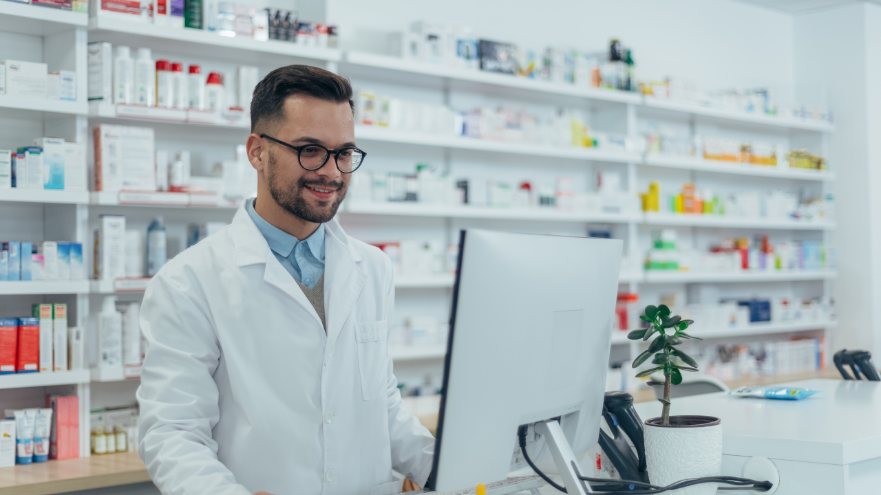 Pharmacist working on a computer, smiling. 