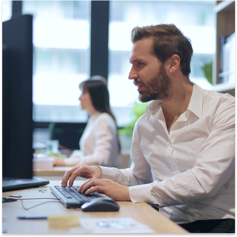 Man in dress shirt working on computer in office environment.