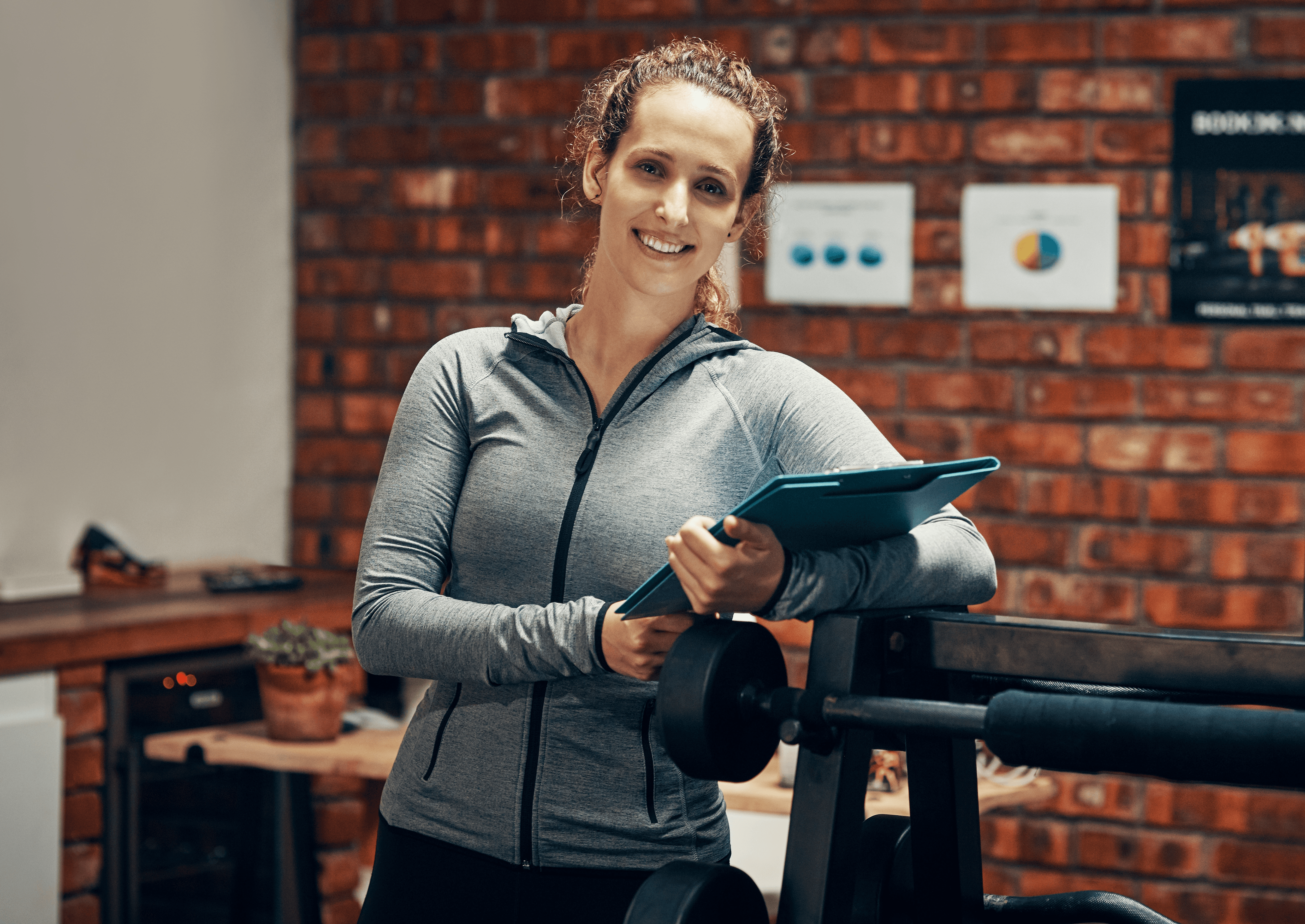 Picture of gym worker holding an iPad and smiling at the camera.