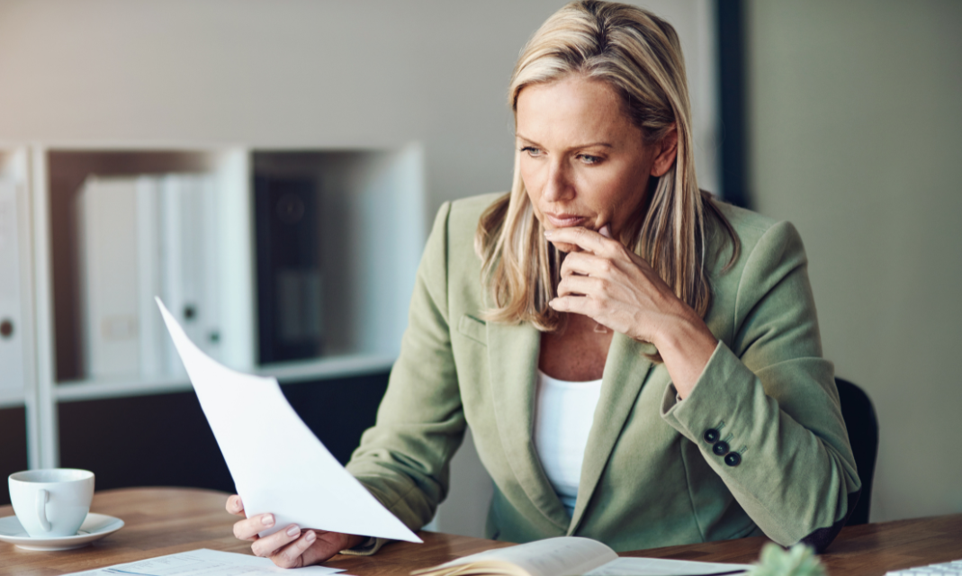 Woman reading a paper document in office attire.